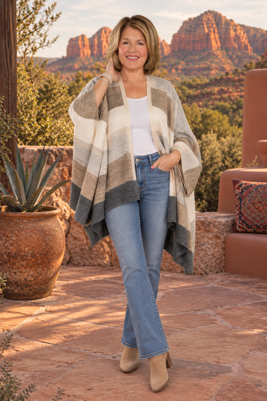 a striped knit poncho with horizontal bands of cream, taupe, brown, and charcoal gray, 